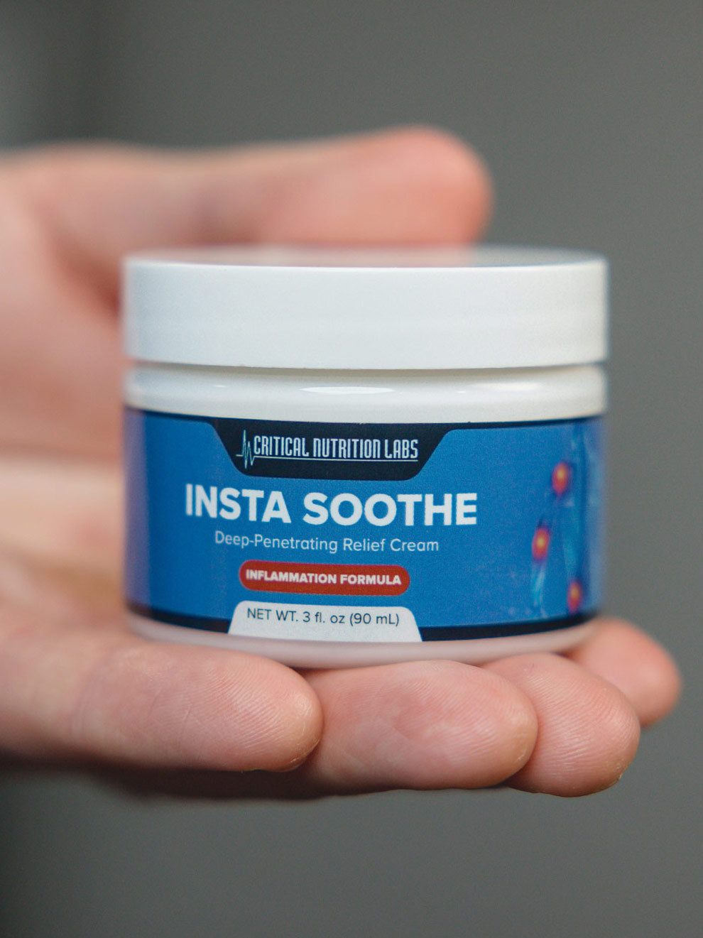 Hand holding a jar of 'Insta Soothe' cream against a neutral background.